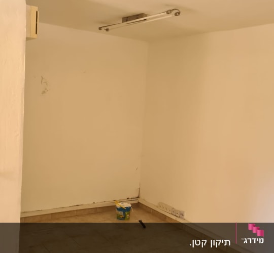 חדר ריק עם דלי צבע וכלי עבודה על הרצפה